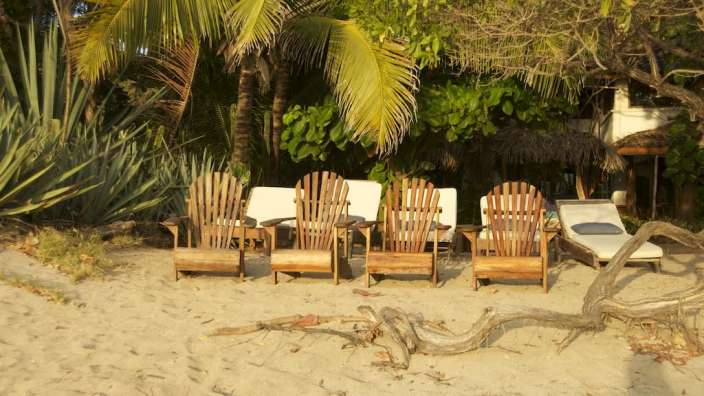 Eine Reihe von Holzstühlen und Liegestühlen am Strand