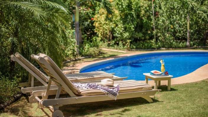 Liegestühle neben einem Swimmingpool mit einer Wassermelone auf einem Tisch