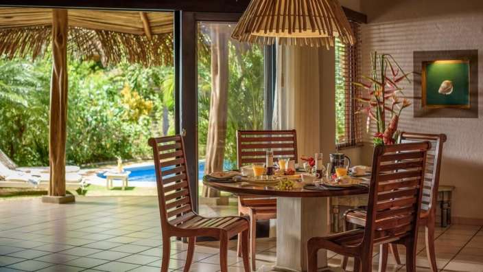Ein Esszimmer mit einem Tisch und Stühlen mit Blick auf einen Pool