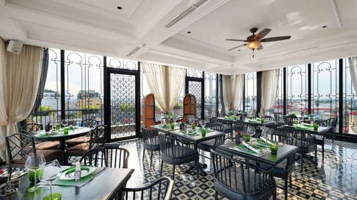 Ein Restaurant mit vielen Tischen und Stühlen und einem Deckenventilator