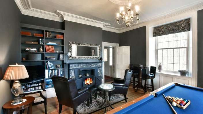 Ein Wohnzimmer mit einem Billardtisch und einem Kamin