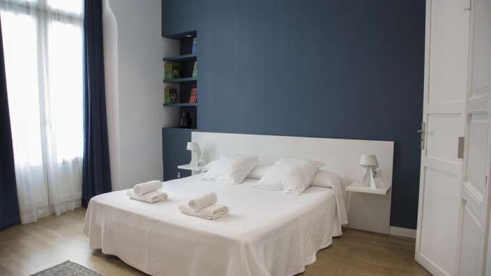 Ein Schlafzimmer mit einem weißen Bett und einer blauen Wand