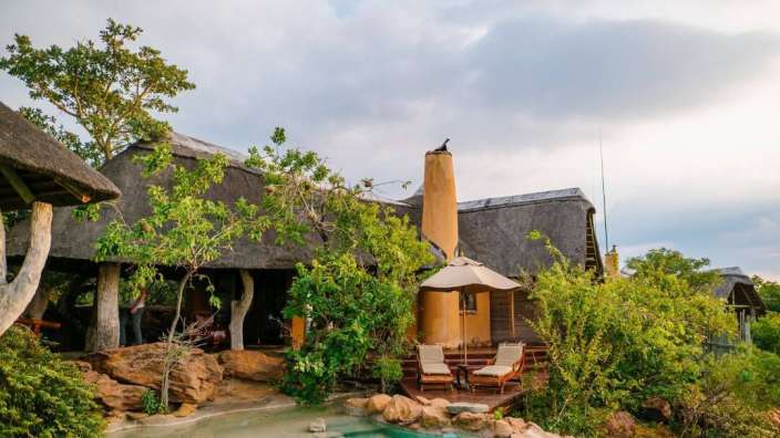 Ein Haus mit Strohdach und einem Pool vorne