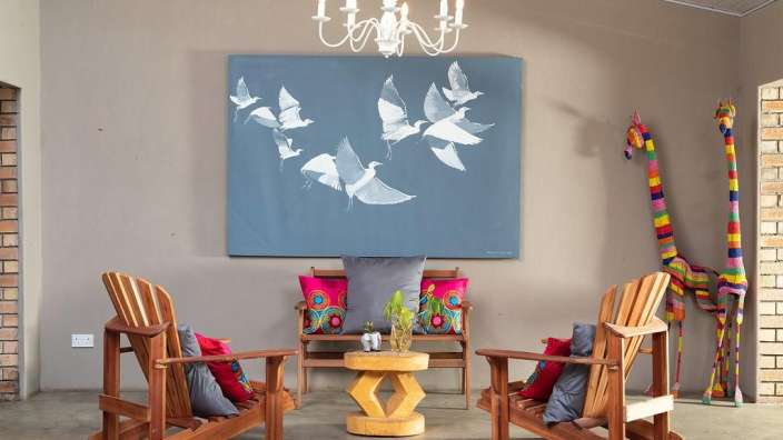 Ein Wohnzimmer mit Stühlen und einem Gemälde an der Wand