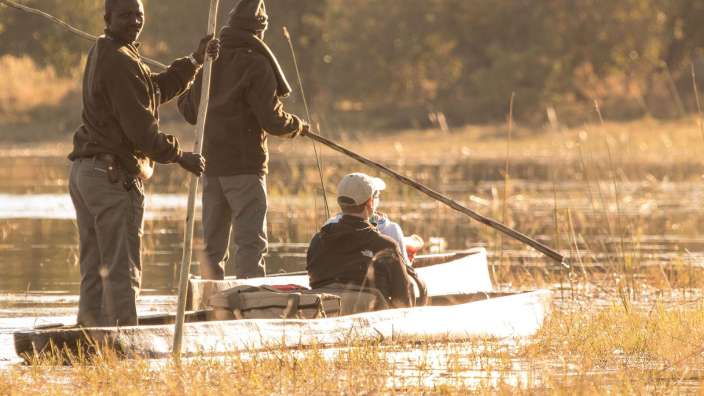 Zwei Männer rudern ein weißes Kanu auf einem Fluss