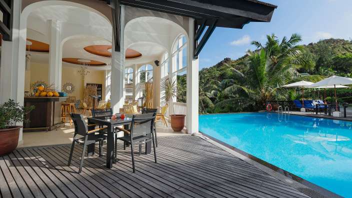 Ein Tisch und Stühle stehen auf einem Holzdeck neben einem Swimmingpool