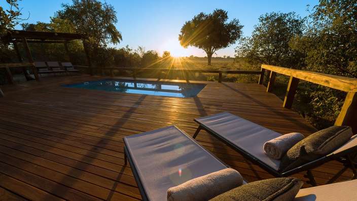 Ein Holzdeck mit Liegestühlen und einem Swimmingpool