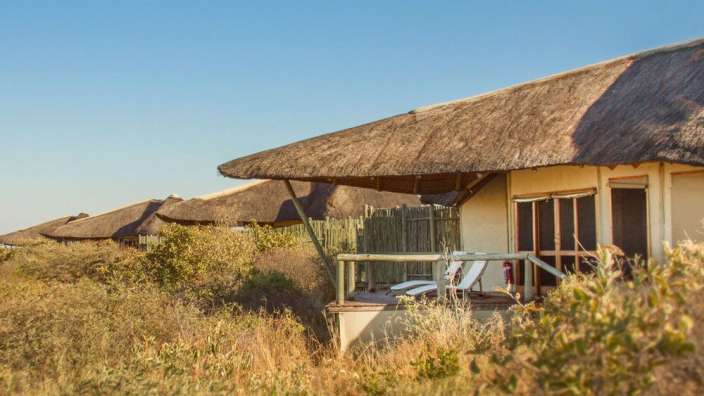 Ein Haus mit Strohdach und einer Terrasse mit Liegestühlen