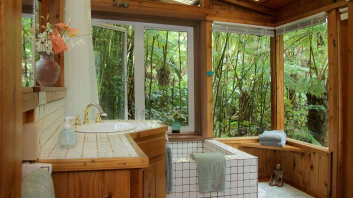 Ein Badezimmer mit einem Waschbecken und einer Badewanne mit Blick auf einen Wald