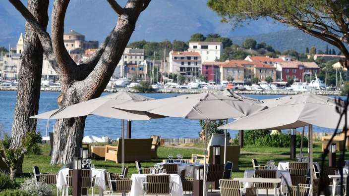 Eine Terrasse mit Tisch und Stühlen mit Blick auf das Wasser