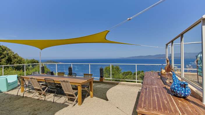 Ein Tisch und Stühle auf einer Terrasse mit Blick auf das Meer