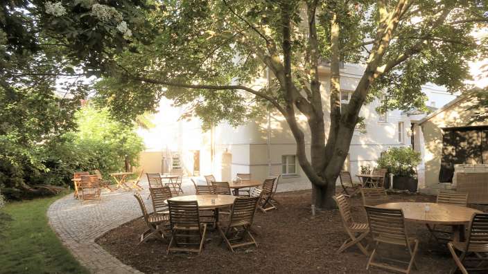 Tische und Stühle in einem Garten mit einem Baum im Hintergrund