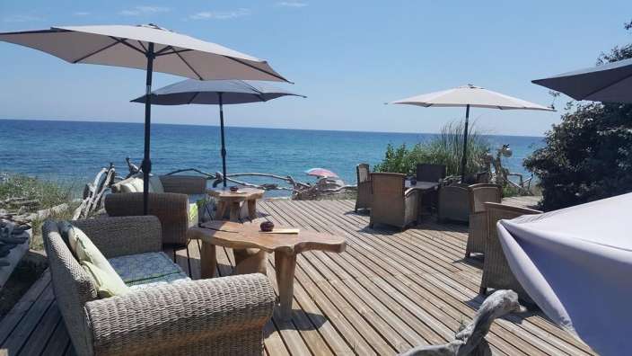 Ein Deck mit Möbeln und Sonnenschirmen mit Blick auf das Meer