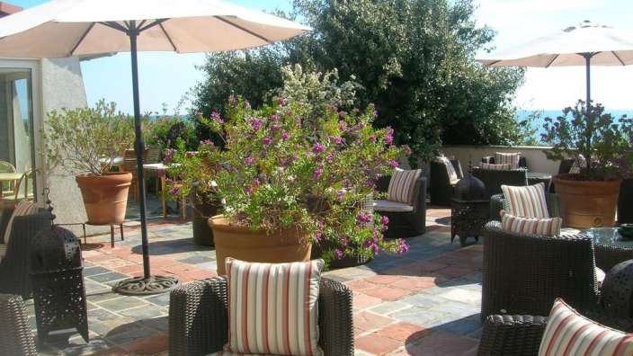 Eine Terrasse mit Stühlen und Tischen und einem großen Blumentopf