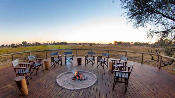 Ein Holzdeck mit Stühlen und einem Feuer