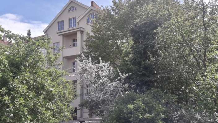 Ein großes Gebäude mit vielen Fenstern und Bäumen davor