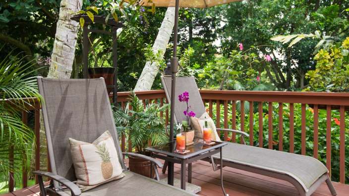 Zwei Liegestühle auf einem Deck mit einem Tisch und einem Sonnenschirm