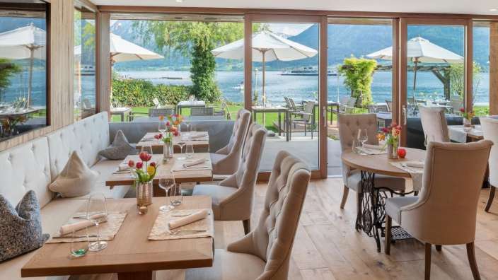 Ein Restaurant mit Blick auf einen See mit vielen Tischen und Stühlen