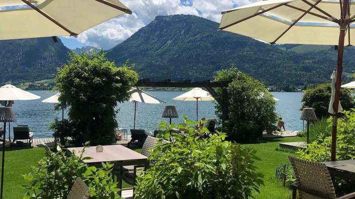 Eine Terrasse mit Tisch und Stühlen mit Blick auf den See und die Berge