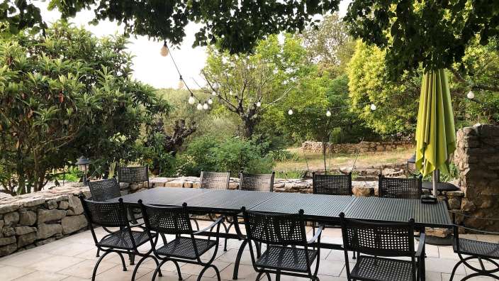 Eine Terrasse mit einem Tisch und Stühlen und einem grünen Regenschirm