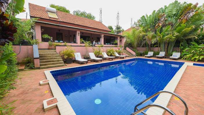 Ein großer Swimmingpool mit Liegestühlen und einem Haus im Hintergrund