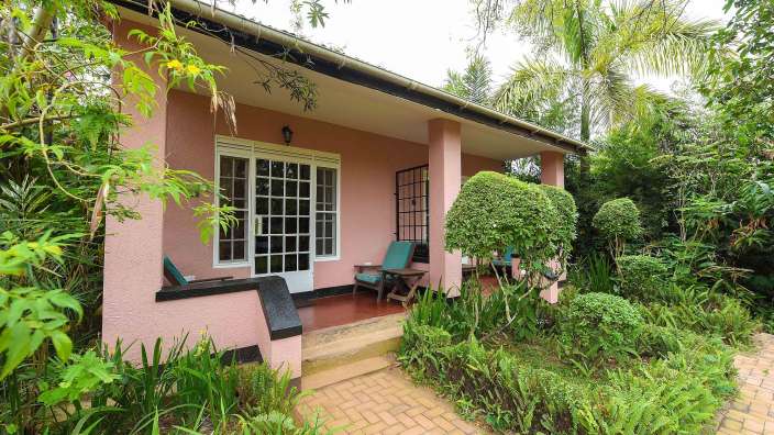 Ein rosa Haus mit einer Veranda und Stühlen davor