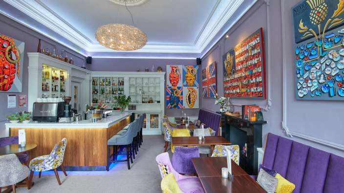 Ein Restaurant mit lila Stühlen und Tischen und einer Bar