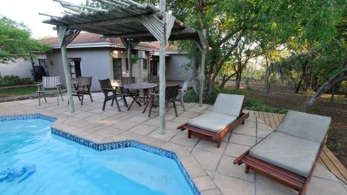 Ein Swimmingpool mit einem Tisch und Stühlen davor