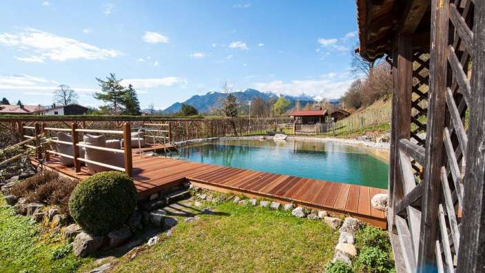 Ein Holzdeck umgibt einen Teich mit Bergen im Hintergrund