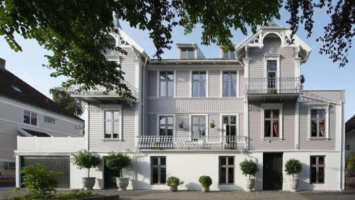 Ein großes graues Haus mit vielen Fenstern und einem Balkon