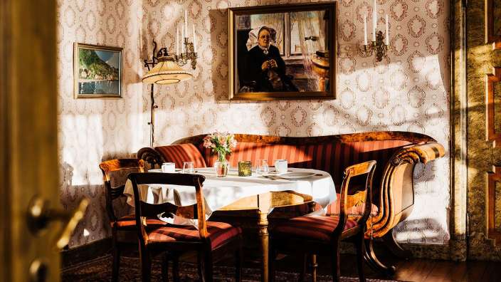 Ein Esszimmer mit einem Tisch und Stühlen und einem Gemälde an der Wand