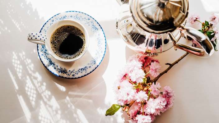 Eine Tasse Kaffee auf einem Untertasse neben einer Teekanne