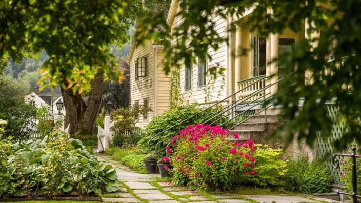 Ein gelbes Haus mit einer Treppe und rosa Blumen