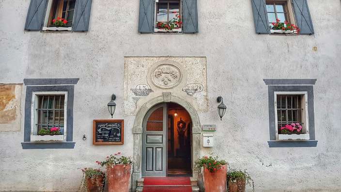 Ein graues Gebäude mit drei Fenstern und einem Schild mit der Aufschrift " gasthaus "
