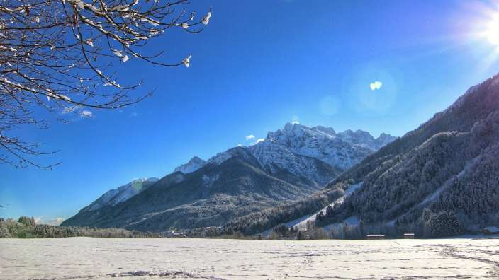 Ein schneebedecktes Feld mit Bergen im Hintergrund