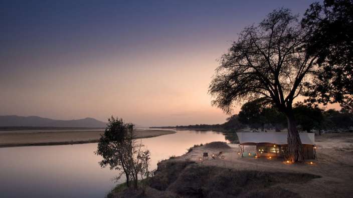 Ein weißes Zelt sitzt am Ufer eines Flusses