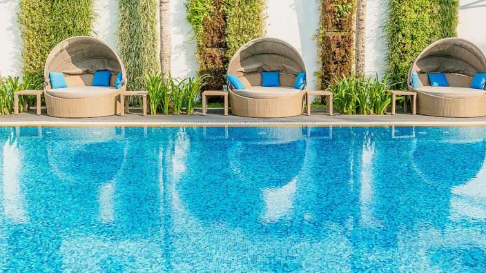 Liegestühle neben einem Swimmingpool mit blauen Kissen