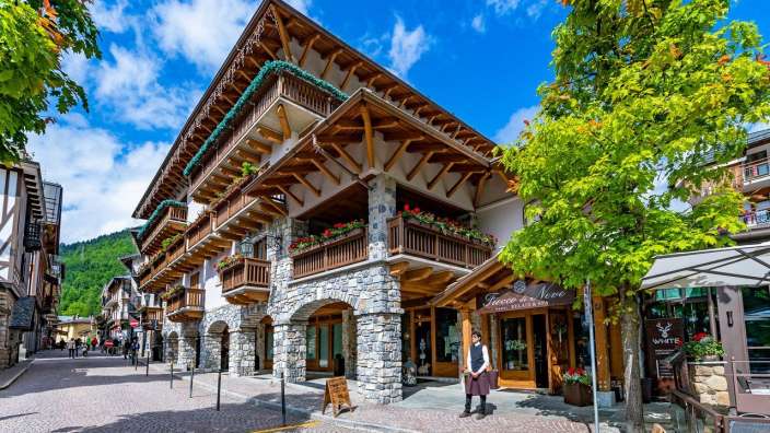 Eine Frau steht vor einem großen Gebäude mit einem Schild, das sagt " fresco di neve "