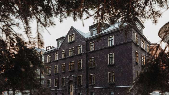 Ein dunkelbraunes Gebäude mit vielen Fenstern steht im Schnee