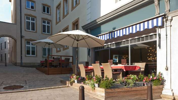 Eine Terrasse mit Tisch und Stühlen vor einem Gebäude