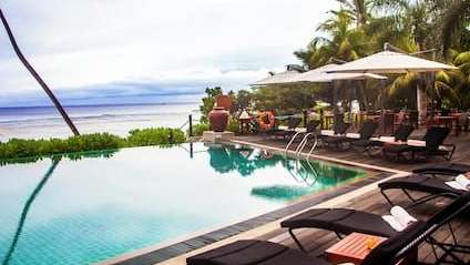 Ein Infinity-Pool mit Liegestühlen und Sonnenschirmen neben dem Ozean .