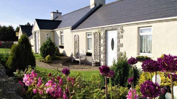 Ein weißes Haus mit einer weißen Tür und einer Bank davor