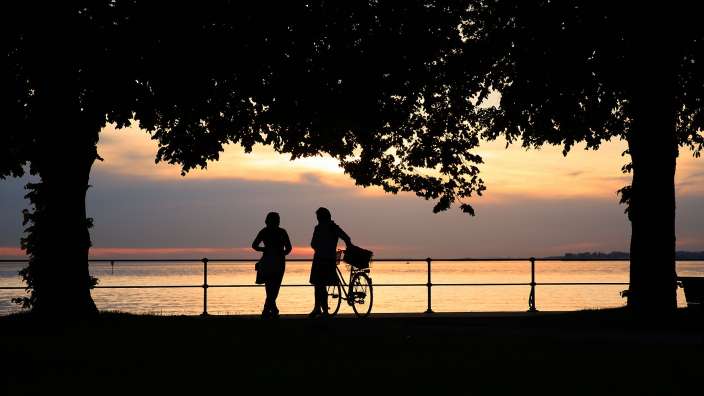 Eine Frau steht neben einem Mann mit einem Fahrrad bei Sonnenuntergang