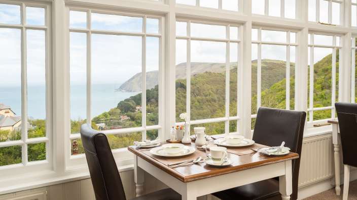 Ein Tisch und Stühle in einem Raum mit Blick auf das Meer