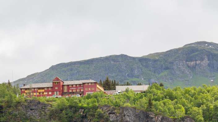 Ein großes rotes Hotel steht auf einem Berghang