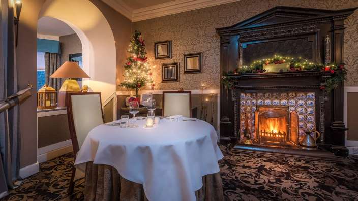 Ein Tisch mit einem weißen Tischtuch steht vor einem Kamin