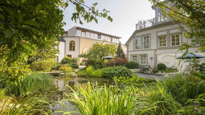 Ein Garten mit einem Teich und einem großen Gebäude im Hintergrund
