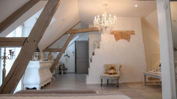 Ein Raum mit einem Bett, einem Stuhl und einem Kronleuchter