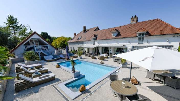 Ein großes Haus mit einem großen Pool und einem Tisch und Stühlen