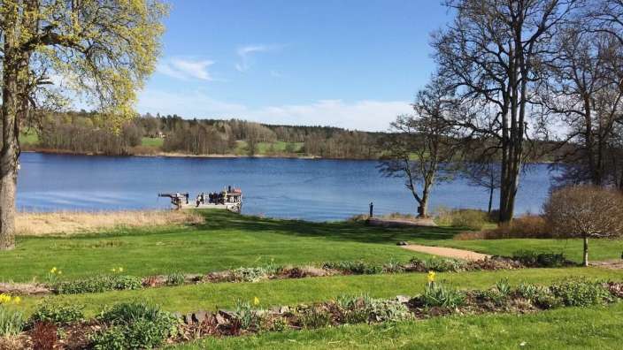 Eine Gruppe von Menschen sitzt auf einem Dock am Ufer eines Sees